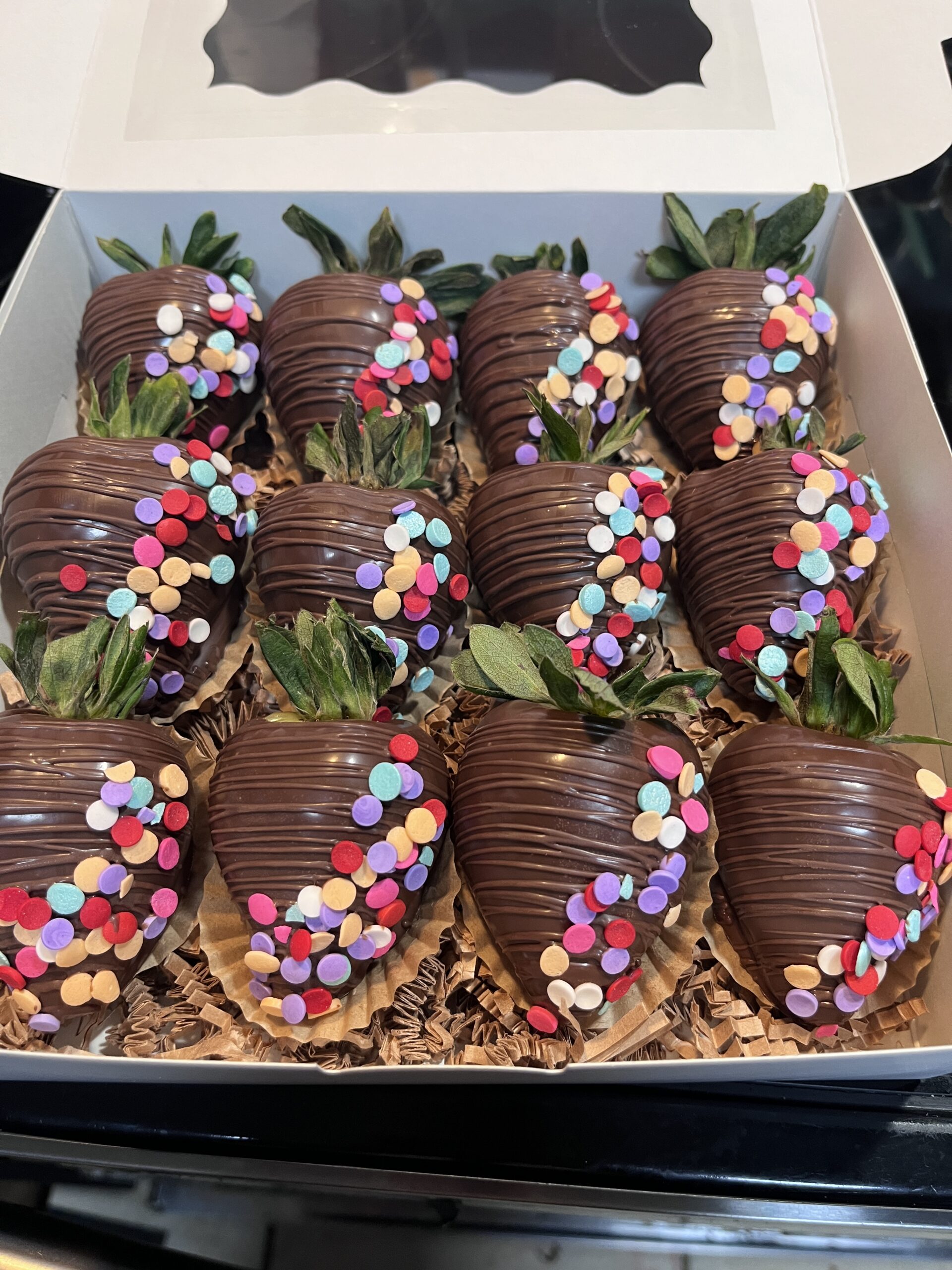Chocolate-covered strawberries topped with colorful sprinkles in a gift box