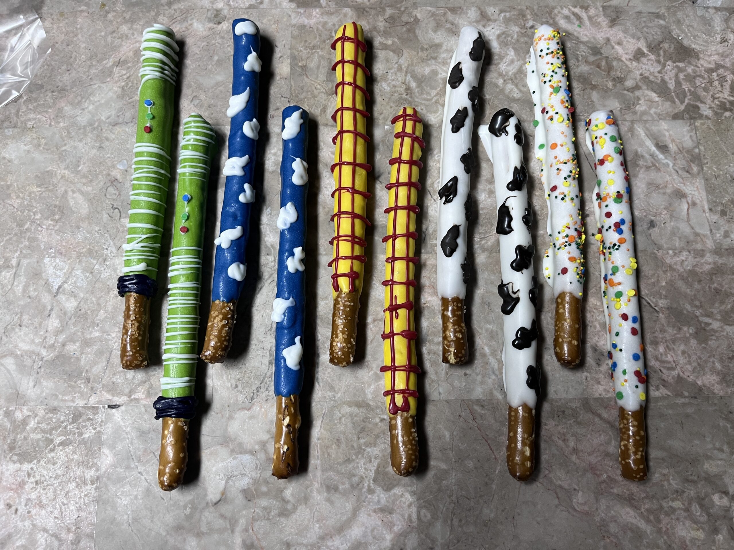 Chocolate-covered pretzel rods decorated with colorful icing and sprinkles