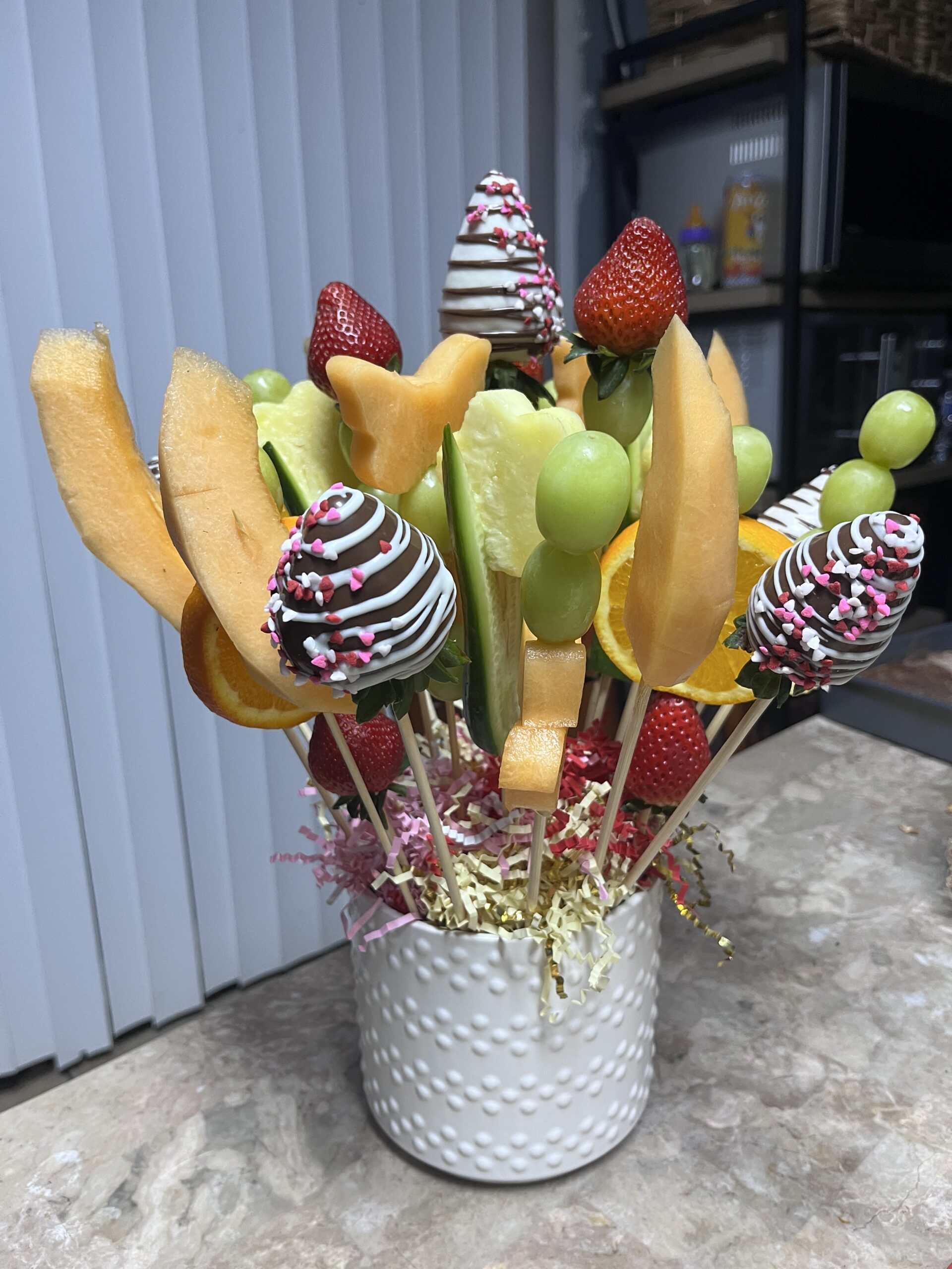 Fruit arrangement with fresh fruit and chocolate-dipped strawberries on decorative sticks