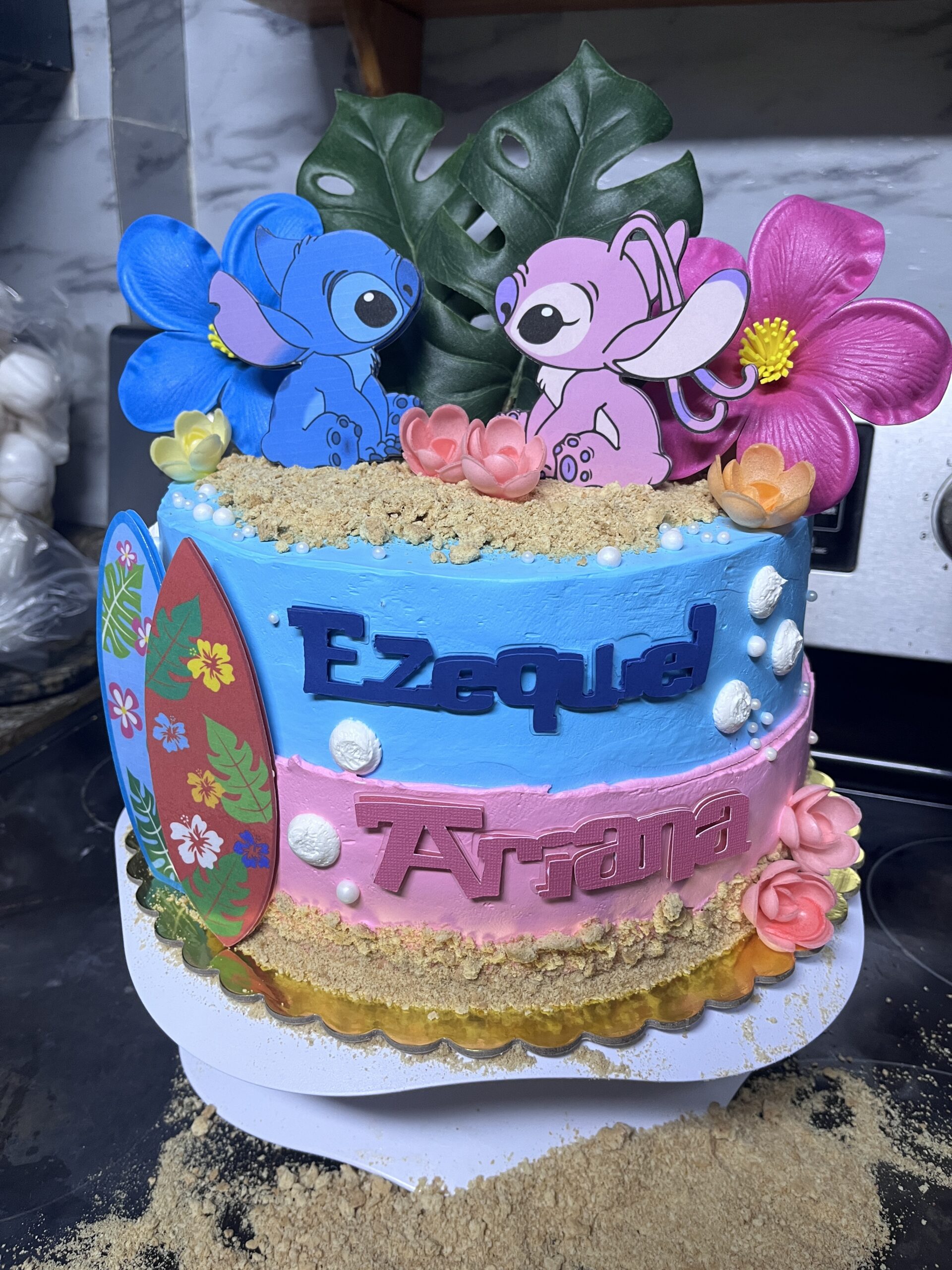 Custom decorated layer cake with blue and pink frosting, flowers, and character toppers
