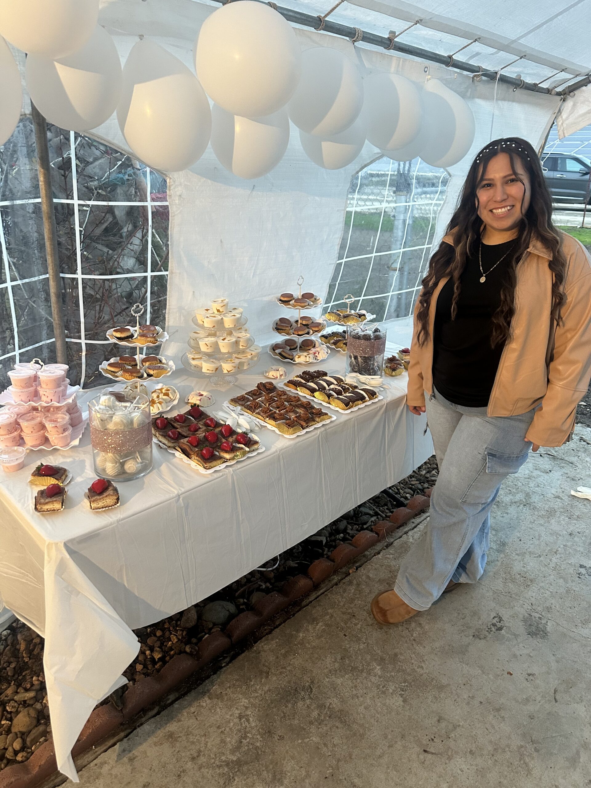 Alondra Duran standing beside a dessert display table at an outdoor event